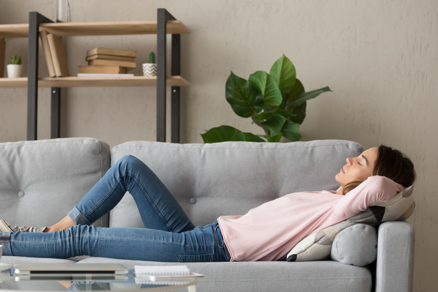 Tired young woman lying on cozy couch take nap daydreaming in living room, peaceful girl relax on comfortable sofa with eyes closed sleeping resting at home, female feel fatigue fall asleep